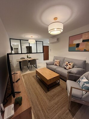 Un salon moderne comprenant un canapé, une table basse et un coin repas avec des chaises et une table.
