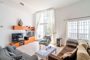 Ein modernes Wohnzimmer mit Flachbildfernseher, einer Couch, einem Couchtisch und einem Sessel.