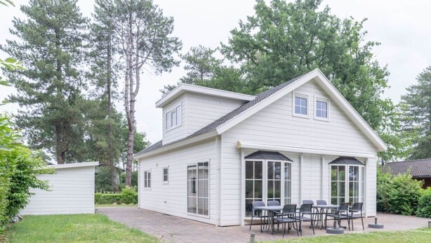 Een wit huis met twee verdiepingen, een overdekte patio en een zitgedeelte buiten.