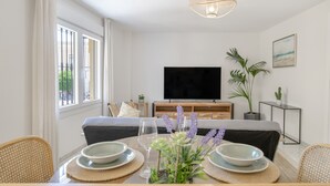 A modern living room with a television, dining table, chairs, and a sofa.