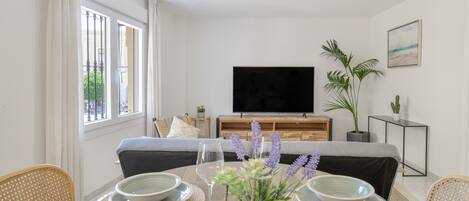 Una sala moderna con televisor, mesa de comedor, sillas y un sofá.