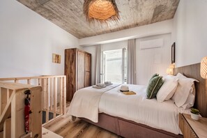 A bedroom with a wooden bed, a view to the outside, a wooden railing, and a ceiling with a textured design.