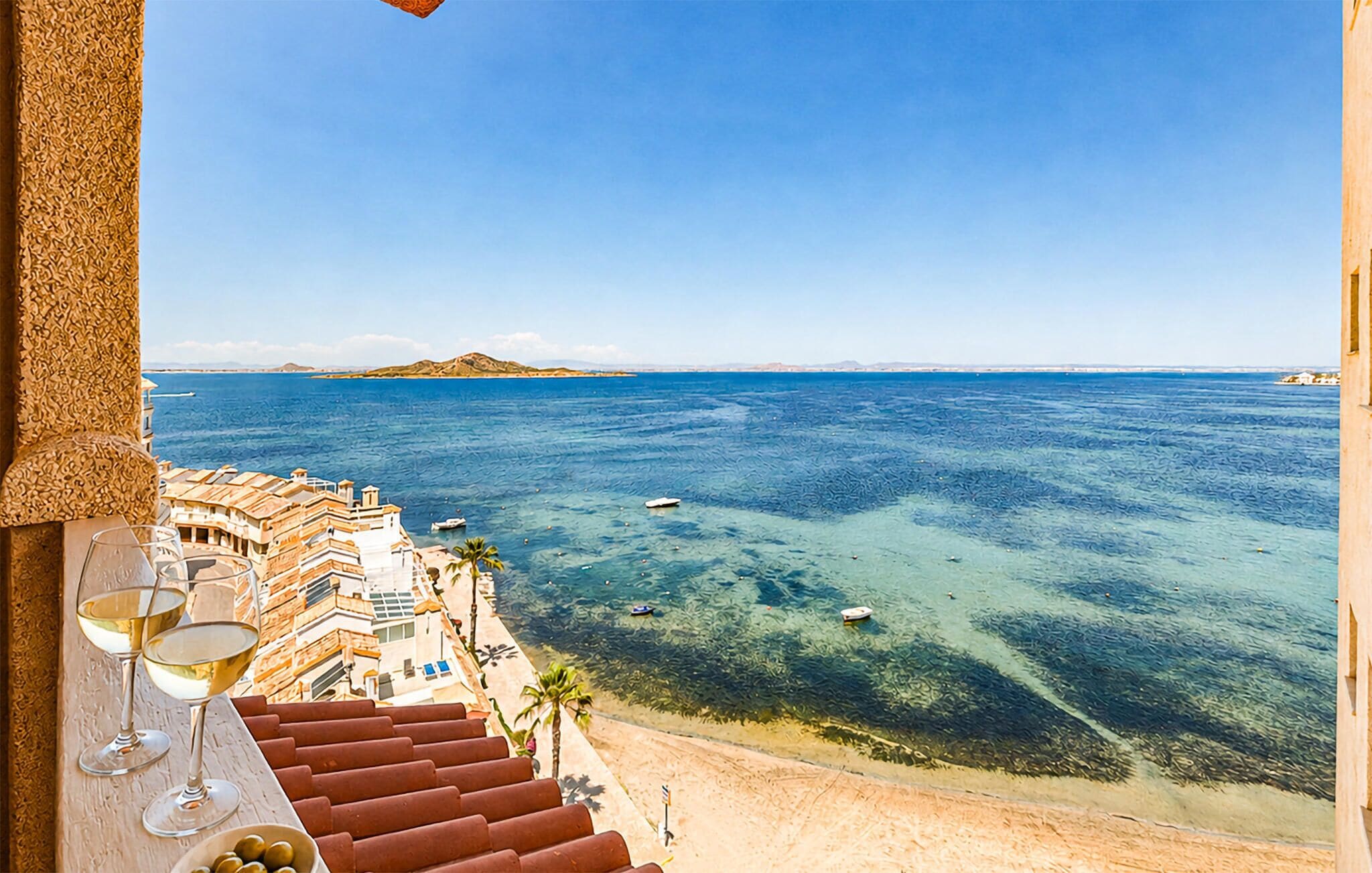 Une chambre d’hôtel située en bord de mer, avec vue sur la mer, un balcon avec quelques marches et une table à manger agrémentée de verres à vin.