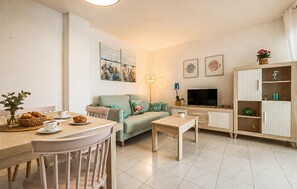 Ein Wohnzimmer mit Sofa, Couchtisch, Fernseher und Schrank.