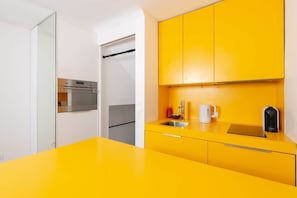 Une cuisine moderne avec des meubles de couleur jaune, un four en acier inoxydable, un évier et une machine à café.