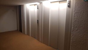 Ein Teppich ausgelegter Korridor, der zu einer Reihe geschlossener Aufzugtüren führt.
