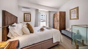 A modern bedroom with a large bed, a bedside table, a small sofa, and a glass partition.