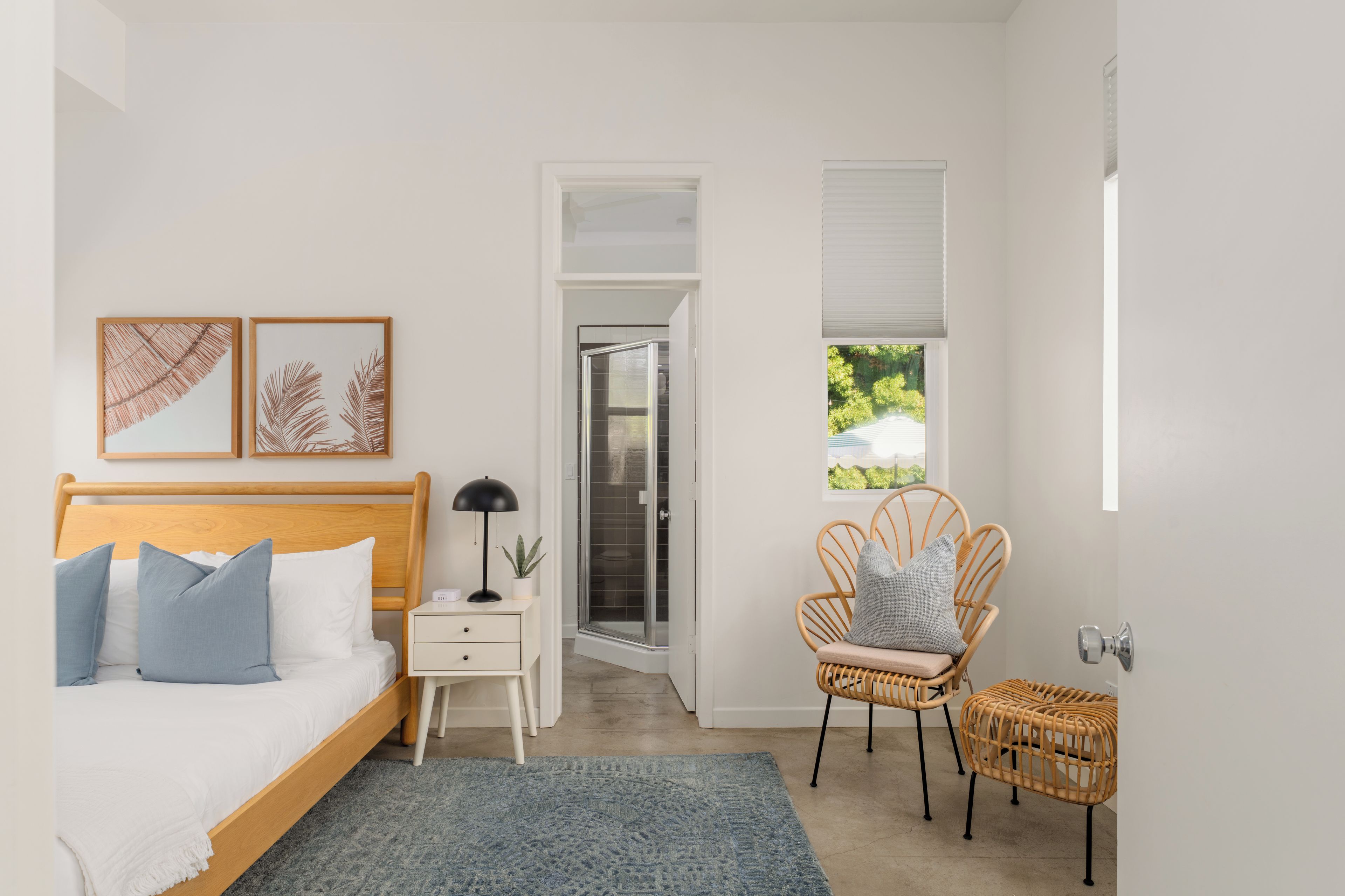 A bedroom with a bed, bedside table, lamp, and a chair.