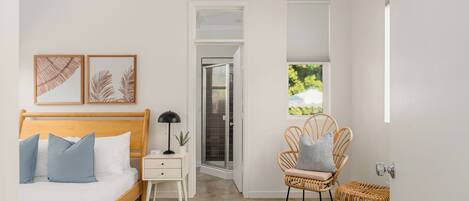 A bedroom with a bed, bedside table, lamp, and a chair.