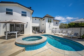 Ein Garten mit Schwimmbad, Whirlpool und Gartenmöbeln.