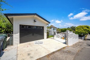 A 1-car driveway parking space with a garage, a gated fence, and a pool area in the background. - Family Beach House w/ Pool & AC + Walking Distance to Shops + Food (Encinitas)