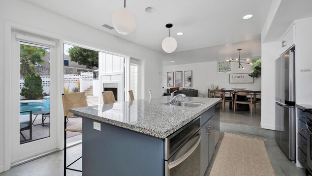 Een moderne keuken met een groot eiland, roestvrijstalen apparatuur en een eetgedeelte met uitzicht op de omgeving.
