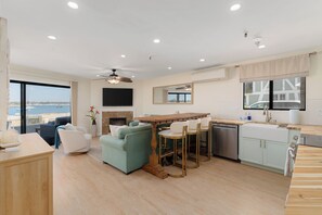 A modern living room with a sofa, chairs, a dining table, and a kitchen area with a dishwasher. - Ground Floor Waterfront | AC | Private Patio (San Diego)
