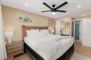 A bedroom with a bed, bedside tables, a ceiling fan, and a bathroom visible through an open door. - Ground Floor Waterfront | AC | Private Patio (San Diego)
