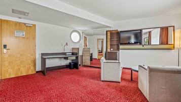 A hotel room with a desk, chair, and a television mounted on the wall.
