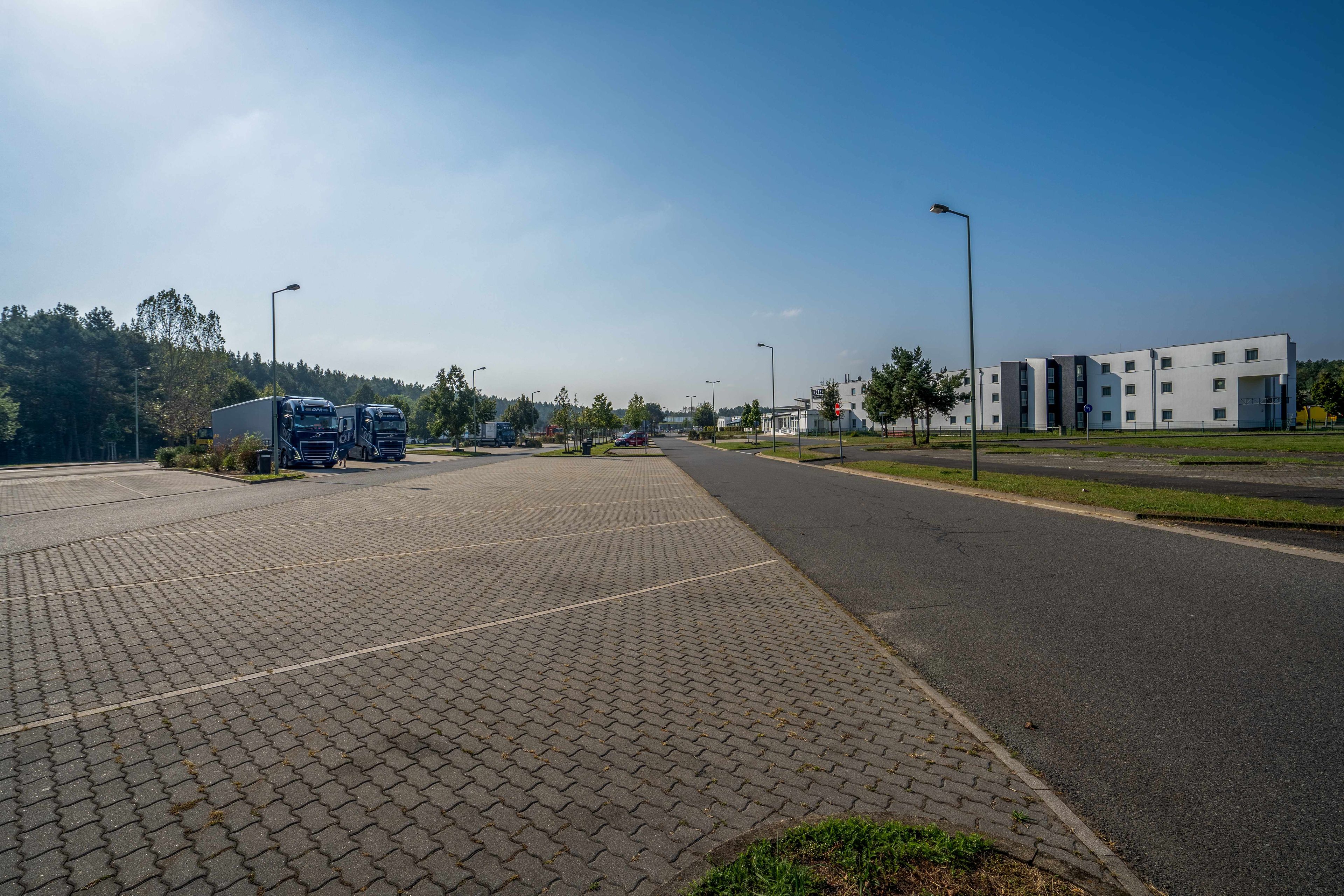A paved area with a road, a building with a modern design, and a clear sky.
