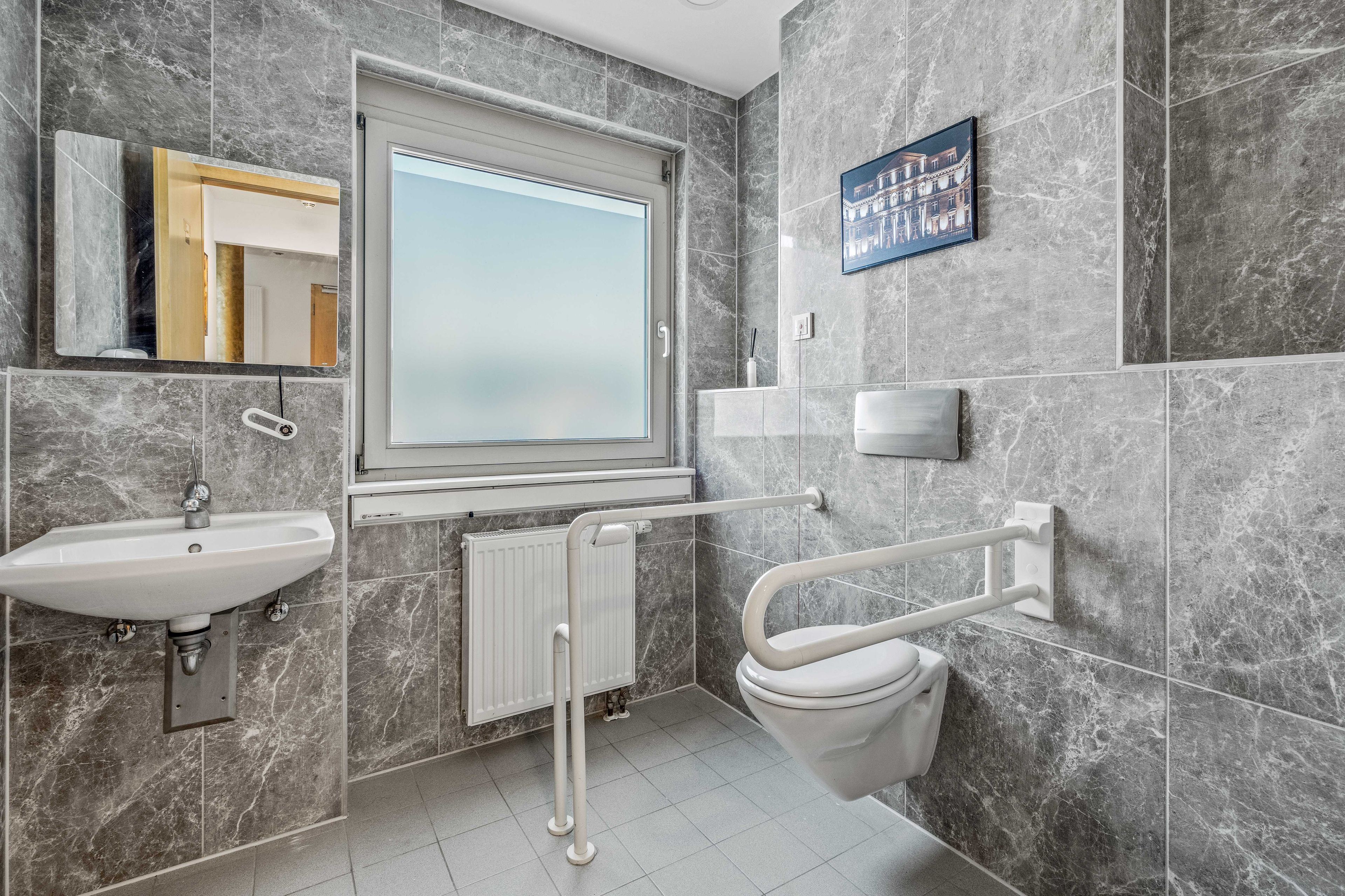 Ein modernes Badezimmer mit Waschbecken, Toilette und Fenster.