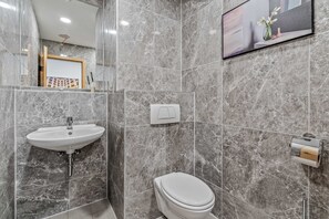 Un baño con lavamanos blanco, inodoro y un cuadro en la pared.