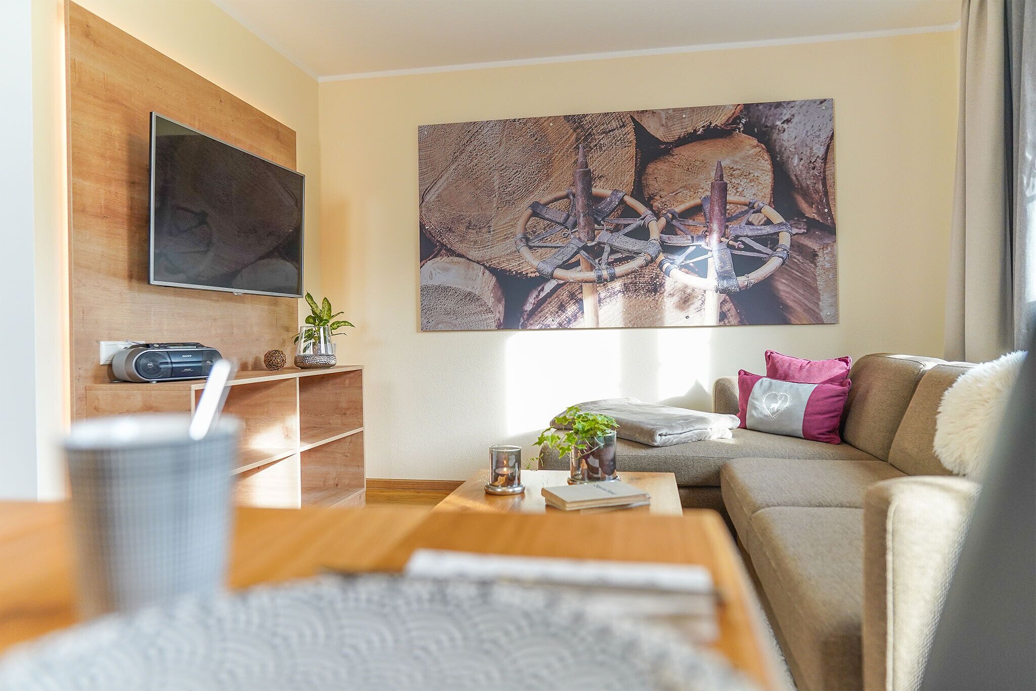 Un salon moderne doté d’un téléviseur à écran plat, d’étagères en bois, d’une table basse, d’un canapé et d’un grand tableau abstrait.