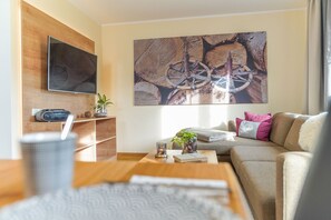 Un salon moderne doté d’un téléviseur à écran plat, d’étagères en bois, d’une table basse, d’un canapé et d’un grand tableau abstrait.