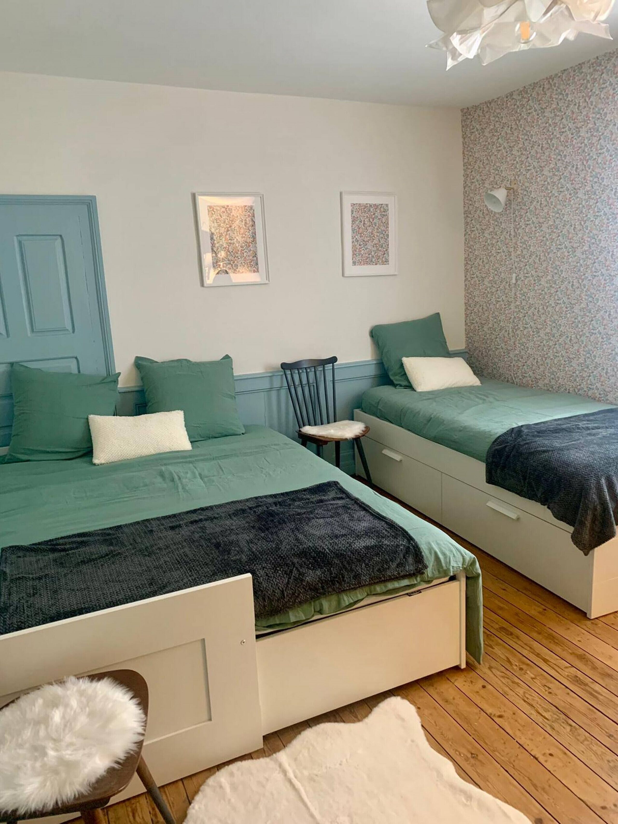 A room with two beds, a chair, a white furry chair, and a white furry rug.