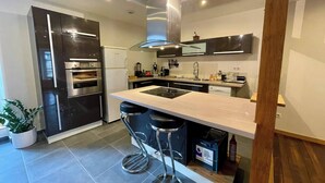 Una cocina moderna con electrodomésticos integrados, una isla central y taburetes de bar.