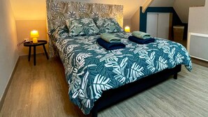 Un dormitorio con una cama, una mesita de noche, una lámpara y una ventana.