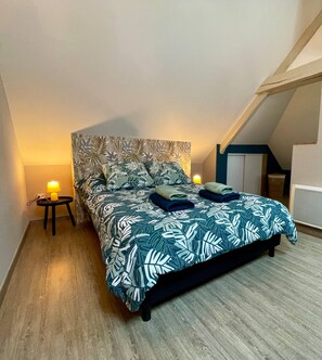 A bedroom with a bed, a nightstand, a lamp, and a window. - EasyHome 19 Duplex  in a quiet location (Vitré)