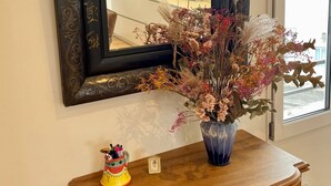 A mirror with ornate frame, a vase with dried flowers, and a small decorative item on a wooden console table.