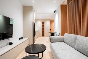 Un salon moderne avec un canapé, un téléviseur, une petite table et une cloison en bois.