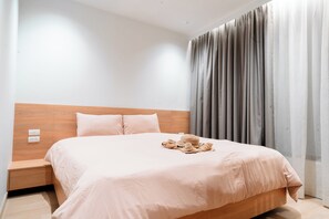 Un lit bien fait, avec une tête de lit, une table de chevet et un rideau.