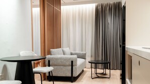 Une pièce moderne comprenant un canapé, deux fauteuils, une petite table et un meuble.