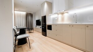 Une cuisine moderne avec un coin repas, des placards intégrés et un réfrigérateur noir.