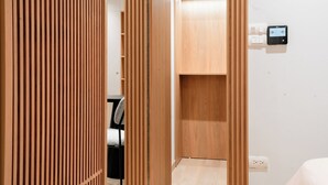 Une pièce comprenant une armoire en bois, un bureau avec une chaise et un thermostat fixé au mur.