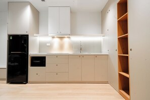 Une cuisine moderne dotée d’appareils électroménagers intégrés, de placards et d’une étagère en bois.