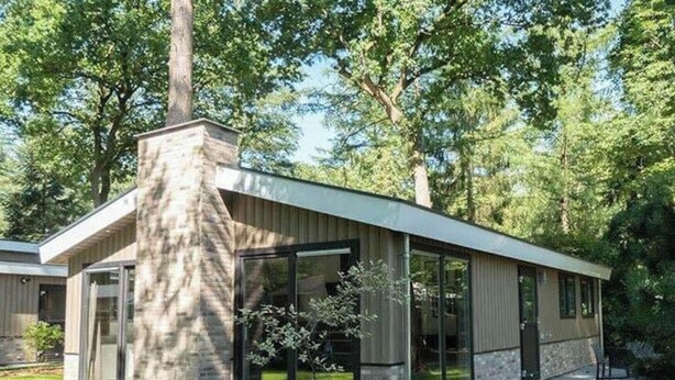 Una casa moderna con chimenea de piedra, grandes ventanales y un patio.