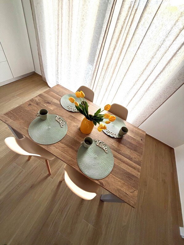 Une table à manger ornée d’un vase de fleurs jaunes, de deux tasses et d’un set de table sur lequel est inscrit un nom.