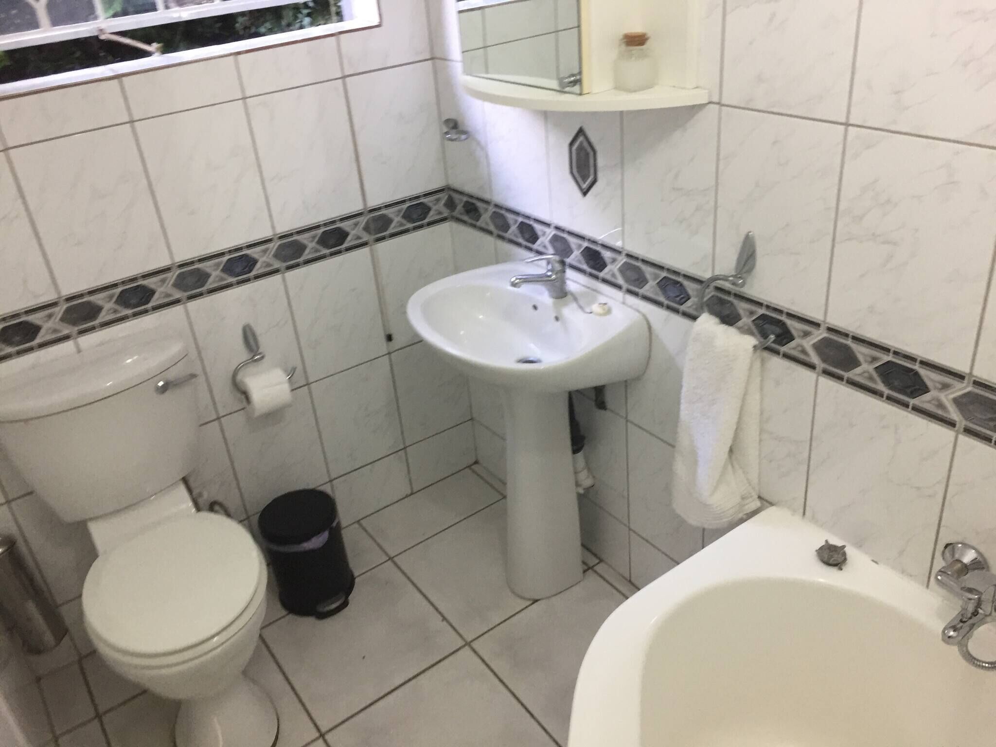 Et badeværelse med toilet, vask og badekar.
