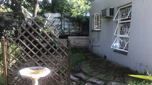 Ein Garten mit einem Kiesweg, einem Metalltor und einem Vogelbad.