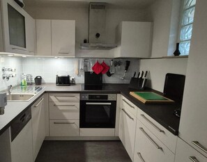 A modern kitchen with white cabinets, a black oven, and a countertop with a cutting board.