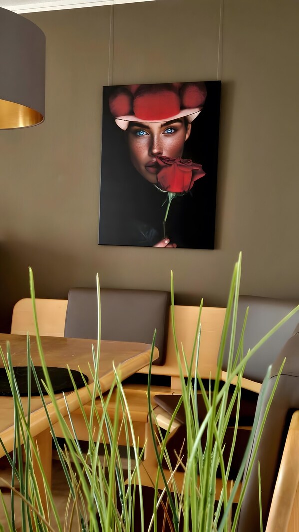 A modern dining area with a table, chairs, and a wall-mounted artwork.