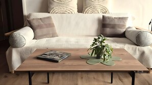 A modern living room with a sofa, pillows, a coffee table, and a painting of a bull.
