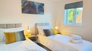 Een hotelkamer met twee bedden, een schilderij aan de muur, een raam met uitzicht en een hanglamp.
