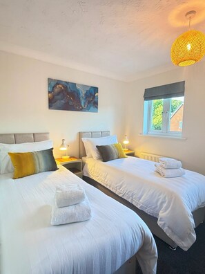 Een hotelkamer met twee bedden, een schilderij aan de muur, een raam met uitzicht en een hanglamp.
