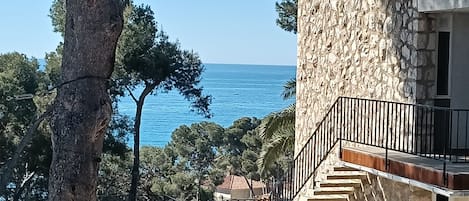 A stone building with a pool and a view of the sea.