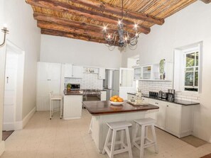 A kitchen with white cabinets, a wooden island, and a chandelier.