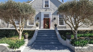 A two-story building with a symmetrical facade, a central entrance with a red door, and a staircase leading to the entrance.