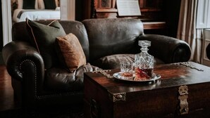 A dark leather sofa with a wooden coffee table in a room with a piano and a bed in the background.