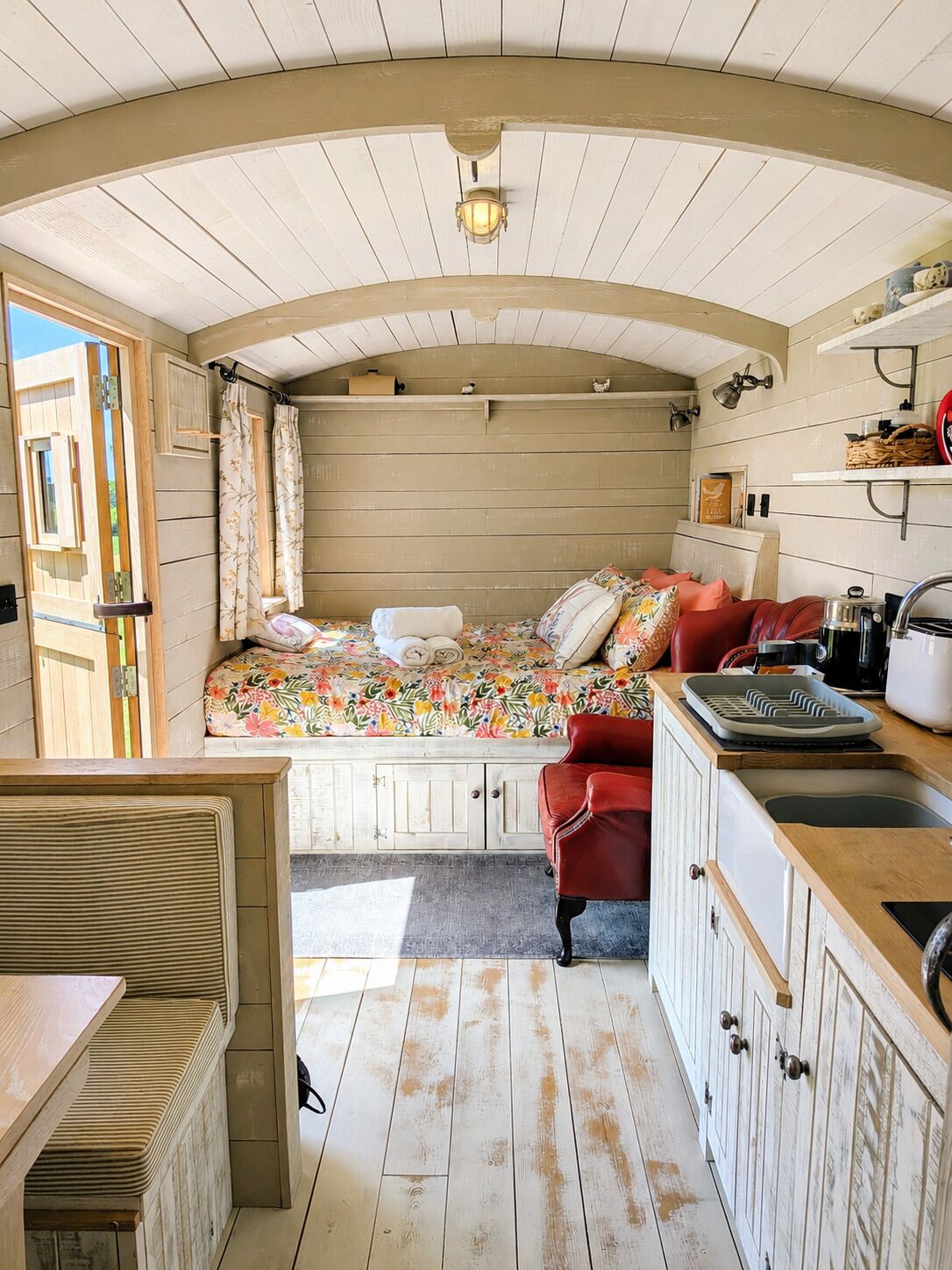 A compact, rustic cabin with a loft bedroom, a kitchenette, and a dining area.