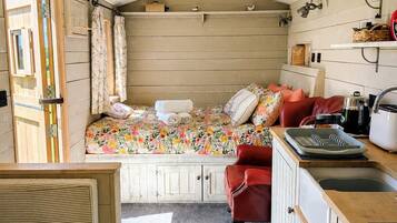 A compact, rustic cabin with a loft bedroom, a kitchenette, and a dining area.